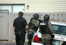 police officers in tactical gear beside patrol car