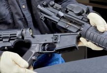 Person assembling a rifle with gloved hands