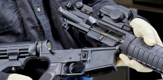 Person assembling a rifle with gloved hands