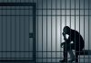 Silhouette of person sitting in a jail cell