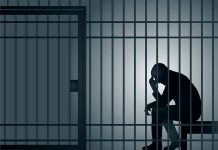 Silhouette of person sitting in a jail cell