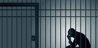 Silhouette of person sitting in a jail cell