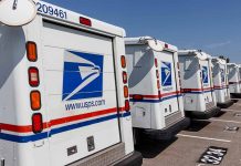Row of USPS mail trucks parked in lot