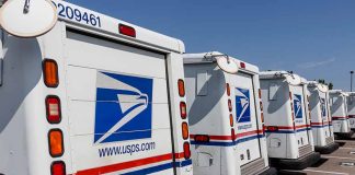 Row of USPS mail trucks parked in lot