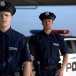 Two police officers standing near patrol car