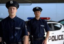 Two police officers standing near patrol car