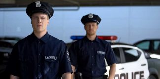 Two police officers standing near patrol car
