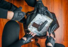 Gloved hands around bag with money and gun