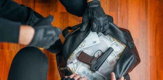 Gloved hands around bag with money and gun