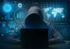 Hacker in hoodie using laptop with digital graphs