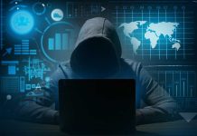 Hacker in hoodie using laptop with digital graphs