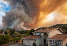 Smoke over house near wildfire in rural area