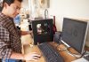 Man operating 3D printer and computer workstation