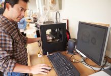 Man operating 3D printer and computer workstation
