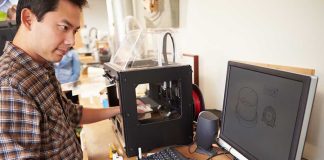 Man operating 3D printer and computer workstation