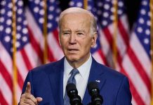 Man speaking at podium with American flags behind