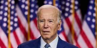 Man speaking at podium with American flags behind