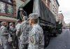 Soldiers gather around a military truck on street