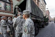 Soldiers gather around a military truck on street