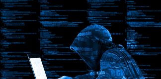 Hooded figure using laptop with code background