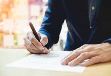 Person signing a document with a pen