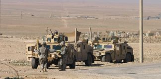 Soldiers beside military vehicles in a desert area