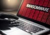 Gloved hand on laptop with ransomware screen