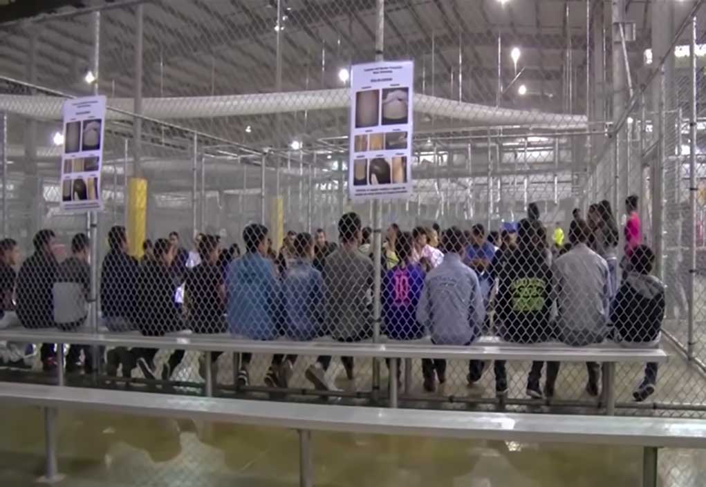 People sitting on benches inside a fenced facility