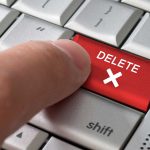 Finger pressing red delete key on keyboard