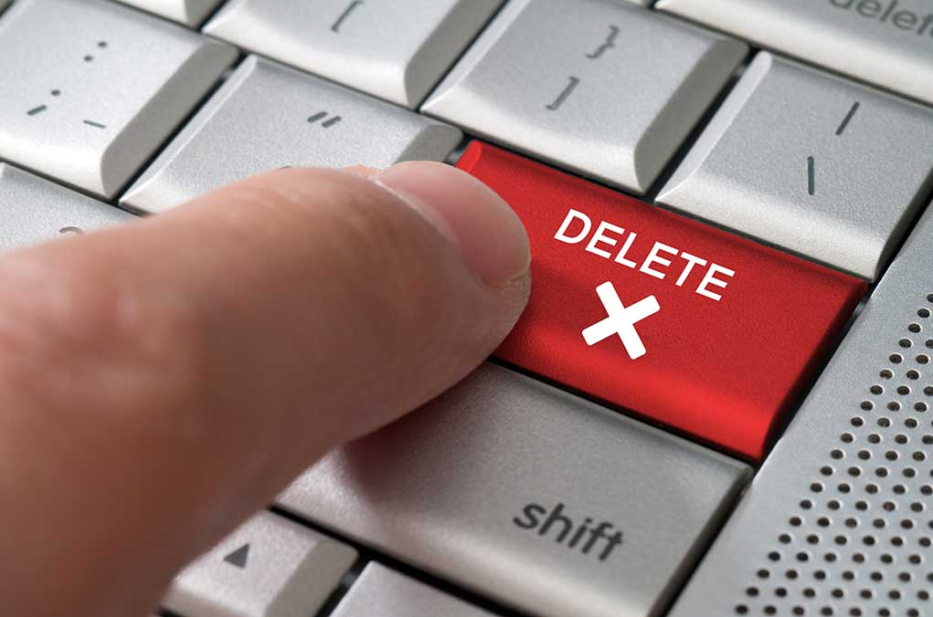 Finger pressing red delete key on keyboard
