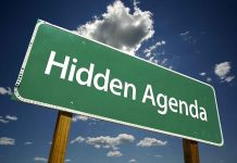 Green road sign reading Hidden Agenda sky background