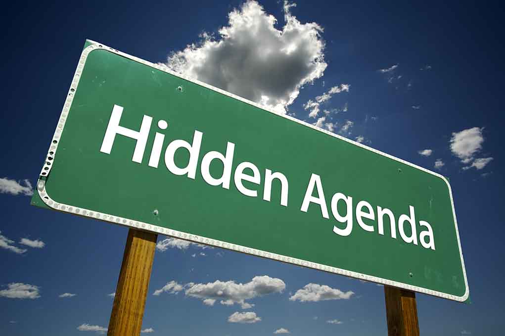 Green road sign reading Hidden Agenda sky background