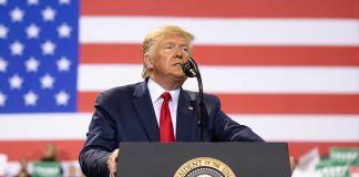 Man speaks at podium with US flag background