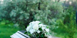 Coffin with white flowers outdoors in green surroundings