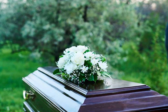 2361639877 featured image Coffin with white flowers outdoors in green surroundings