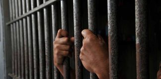Hands gripping prison cell bars tightly