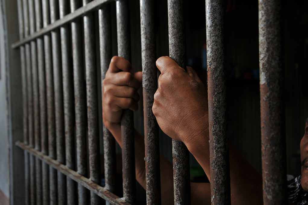 Hands gripping jail cell bars