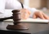 Judge gavel on desk with person writing