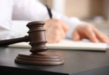 Judge gavel on desk with person writing