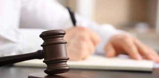 Judge gavel on desk with person writing