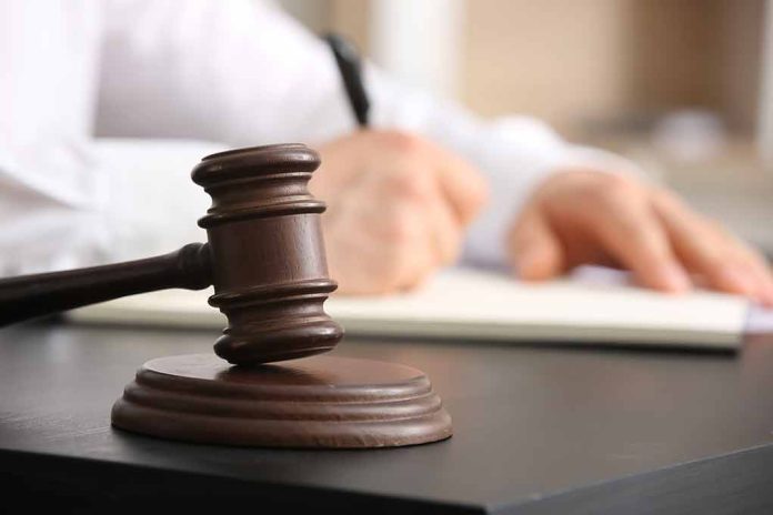 Judge gavel on desk with person writing