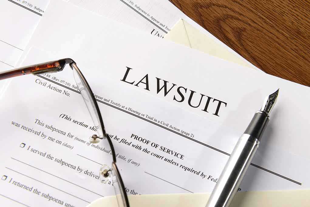 Lawsuit papers with glasses and pen on table