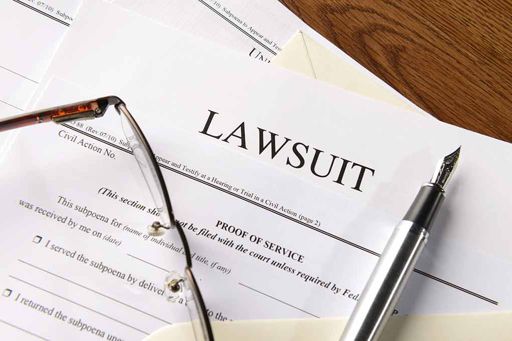 Lawsuit papers with glasses and pen on table