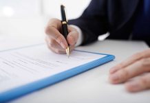 Person signing a document with a pen