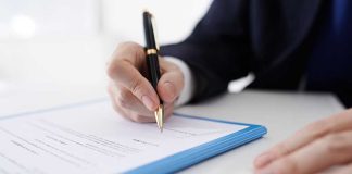 Person signing a document with a pen