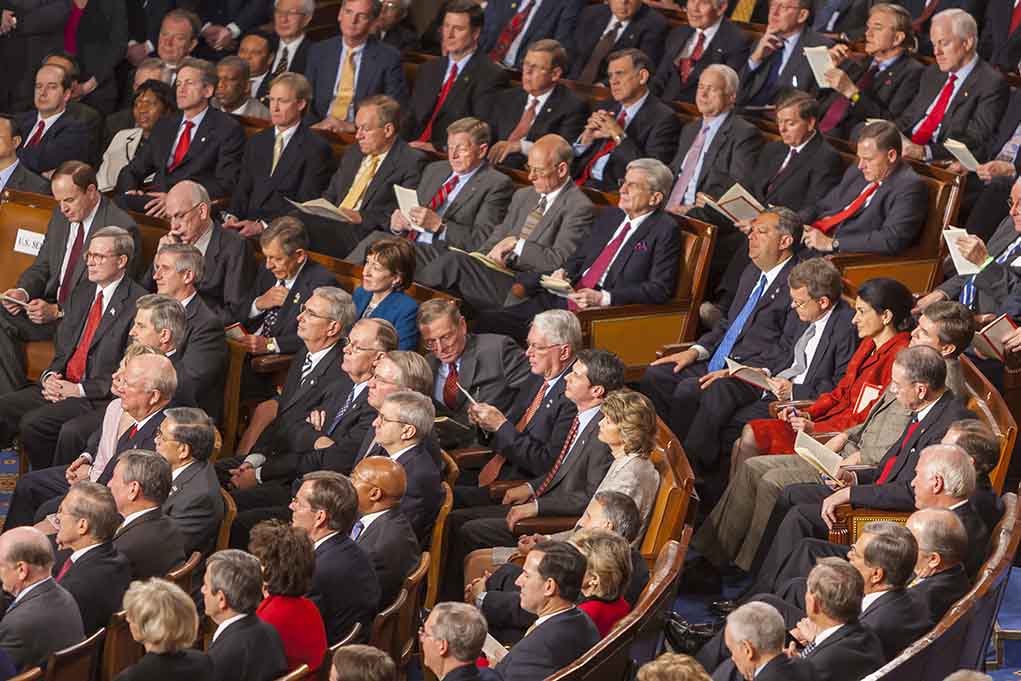 Audience of officials sitting and reading documents in auditorium