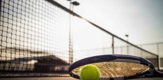 Tennis racket and ball on court near net