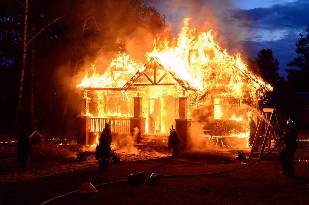 House engulfed in flames with firefighters present