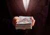 Hand holding a stack of hundred dollar bills