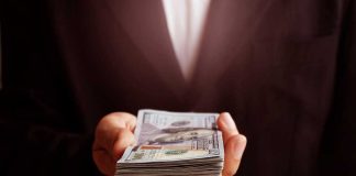 Hand holding a stack of hundred dollar bills